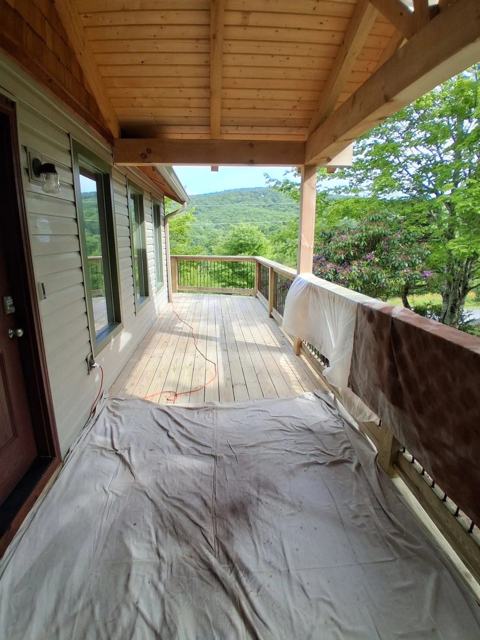 Covered deck staged with drop cloths before staining, mountain view
